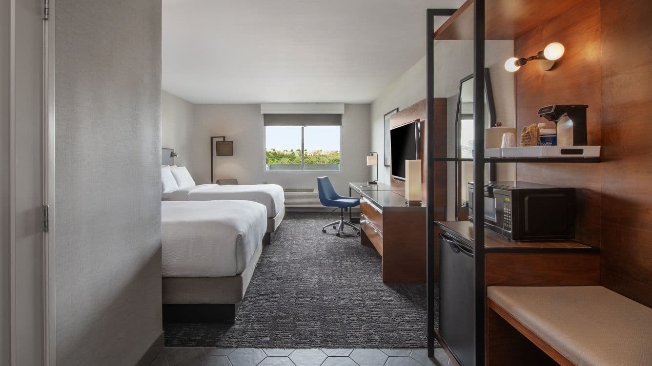 Traditional Double Queen guest room with two queen beds, desk, and media wall